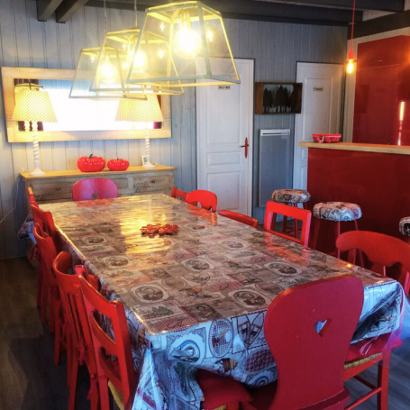 Salle à manger moderne avec une grande table rectangulaire et des chaises rouges.